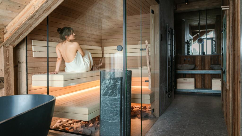 Woman enjoying Tulikivi Naava sauna heater in a scandinavian designed sauna