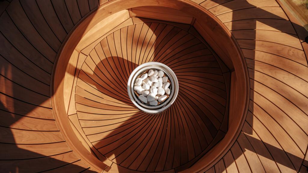 Pyry sauna heater from Tulikivi in a white color inside a beautifully crafted wooden seating in a sauna.